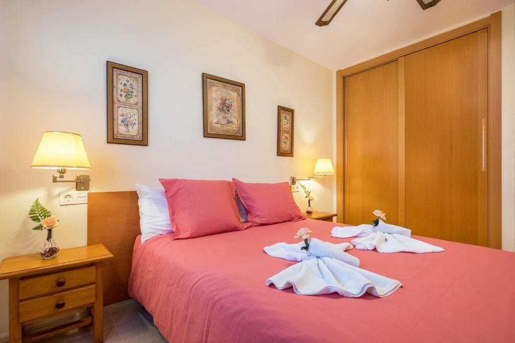 sypialnia z różowym łóżkiem i 2 ręcznikami w obiekcie Apartamento en el Médano w mieście El Médano