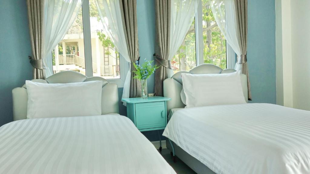twee bedden in een kamer met twee ramen bij Kata Bai D - SHA Certificate Hotel in Kata Beach