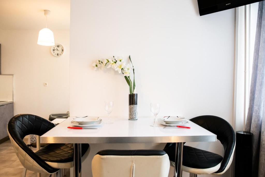 une table blanche avec des chaises et un vase de fleurs. dans l'établissement Le Nazareth -Charmant appartement Lyon Part-Dieu balcon garage, à Lyon