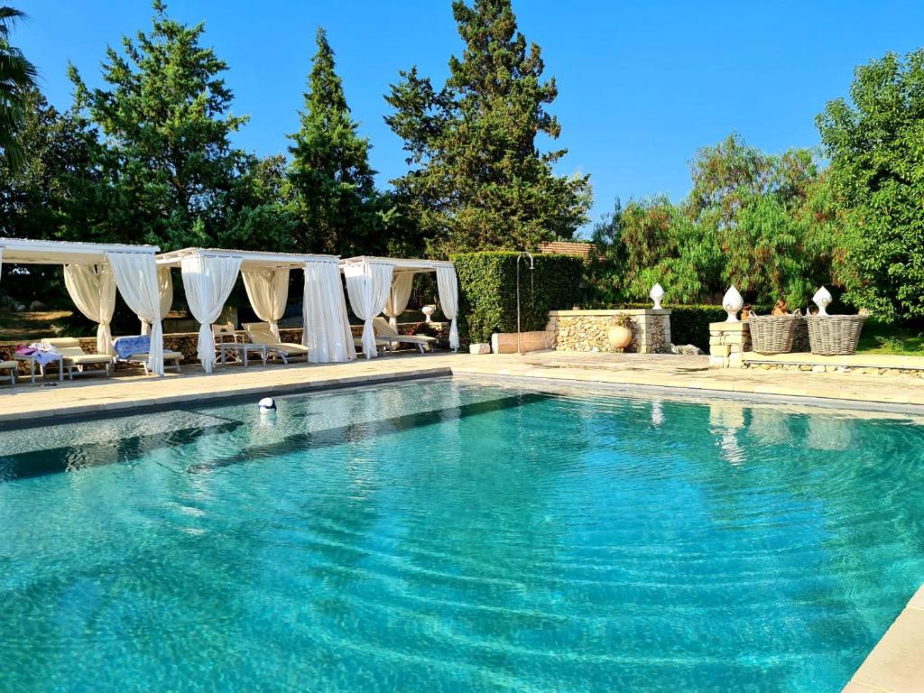 a swimming pool with blue water and white umbrellas at Naturalis Bio Resort in Martano