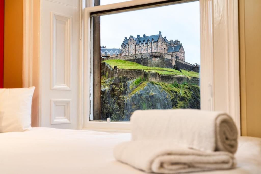 a bedroom with a window with a view of a castle at easyHotel Edinburgh in Edinburgh