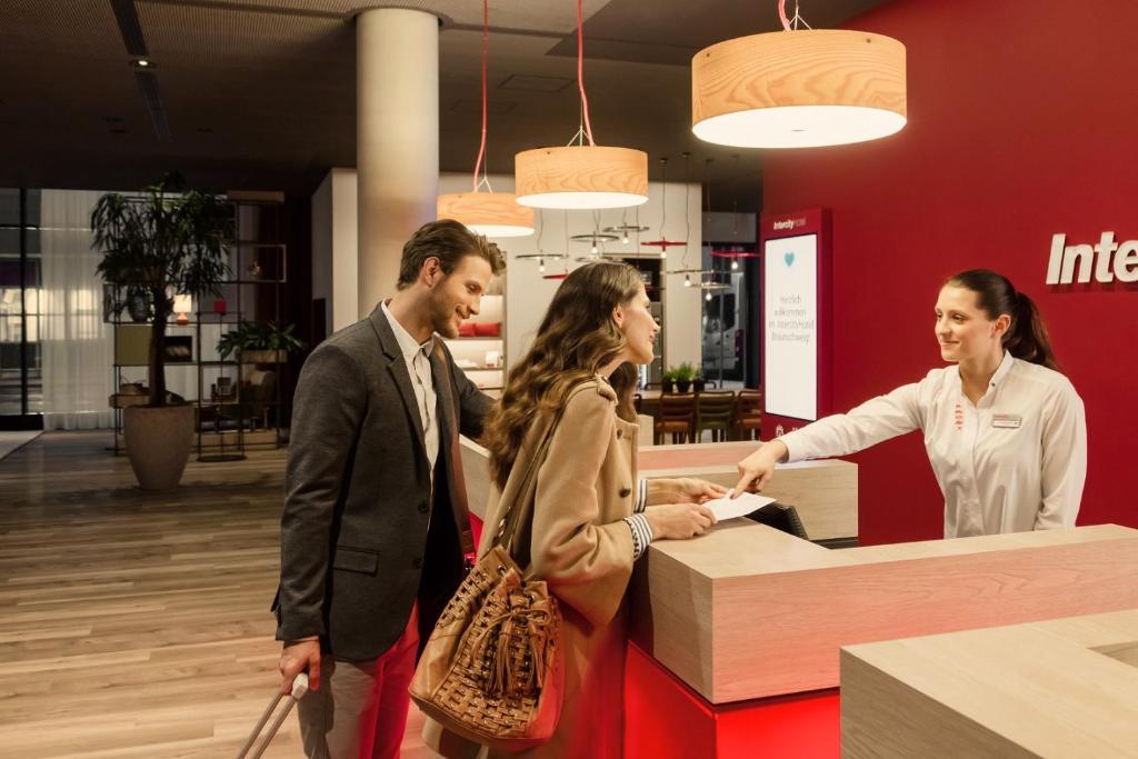 un grupo de personas parados alrededor de un mostrador en una tienda en IntercityHotel Hildesheim, en Hildesheim