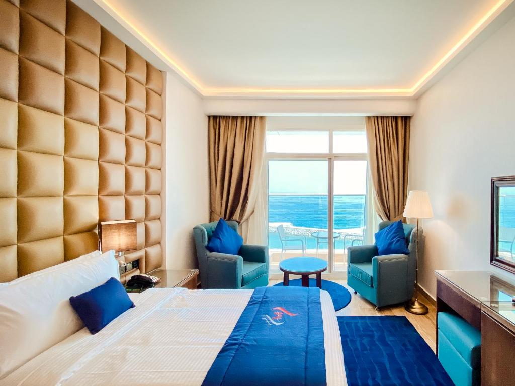 um quarto de hotel com uma cama e duas cadeiras em Mirage Bab Al Bahr Beach Hotel em Dibba