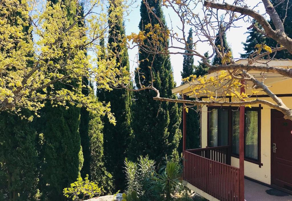 una casa con un porche rojo junto a algunos árboles en Zeleny Mis, en Alupka