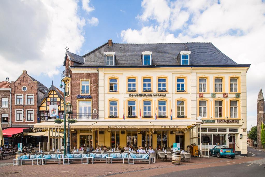 a large yellow building with tables and chairs in front of it at Hotel De Limbourg in Sittard