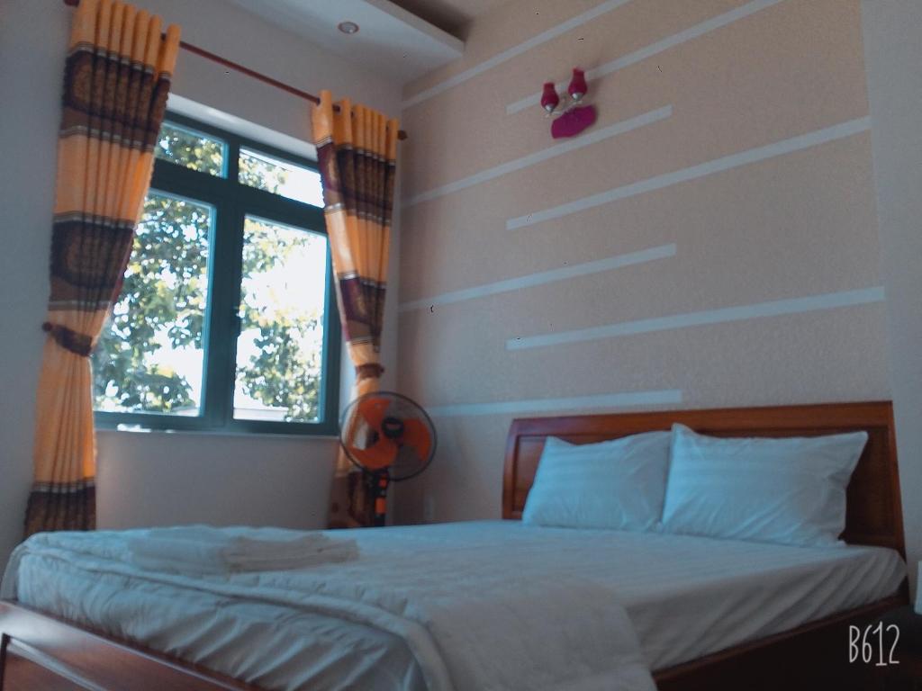 a bedroom with a bed and two windows at Motel Quốc Việt in Bà Rịa