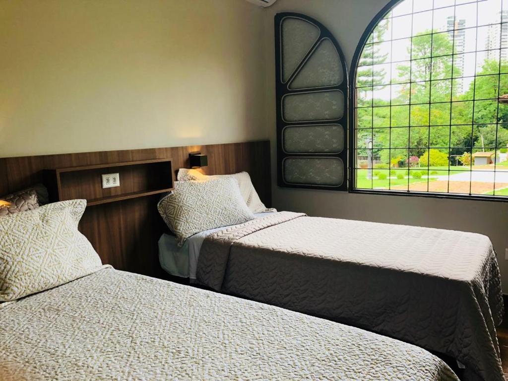 um quarto com 2 camas e uma janela em Hostel SLG em Maringá