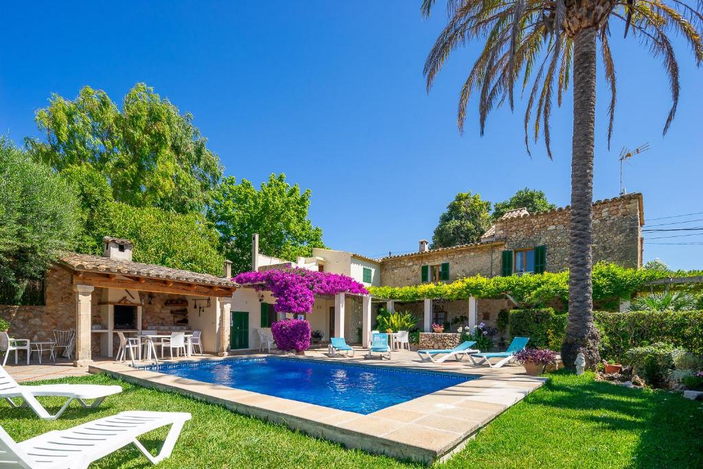 a villa with a swimming pool and palm trees at Can Miquel in Pollença
