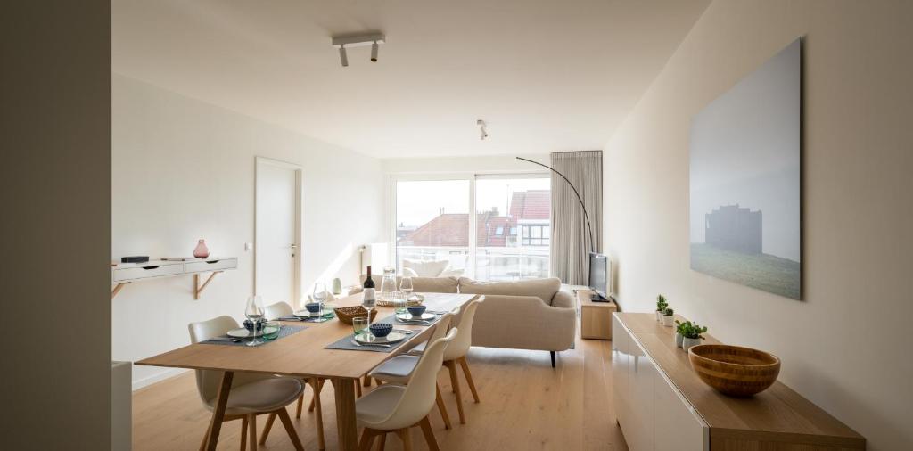 ein weißes Wohnzimmer mit einem Tisch und einem Sofa in der Unterkunft Modern & spacious apartment near beach in Knokke in Knokke-Heist