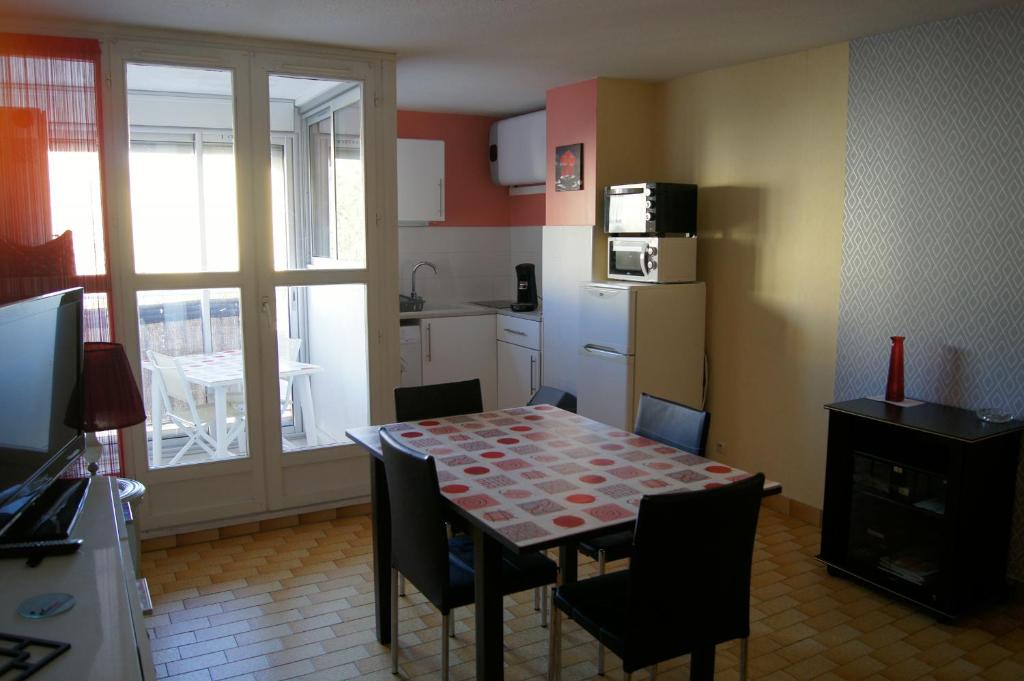 une cuisine avec une table et des chaises et une cuisine avec une fenêtre dans l'établissement Lara 1 - Grand T2 Loggia Sans vis-à-vis Parking - Près centre-port, île des Loisirs, plage Richelieu, au Cap d'Agde