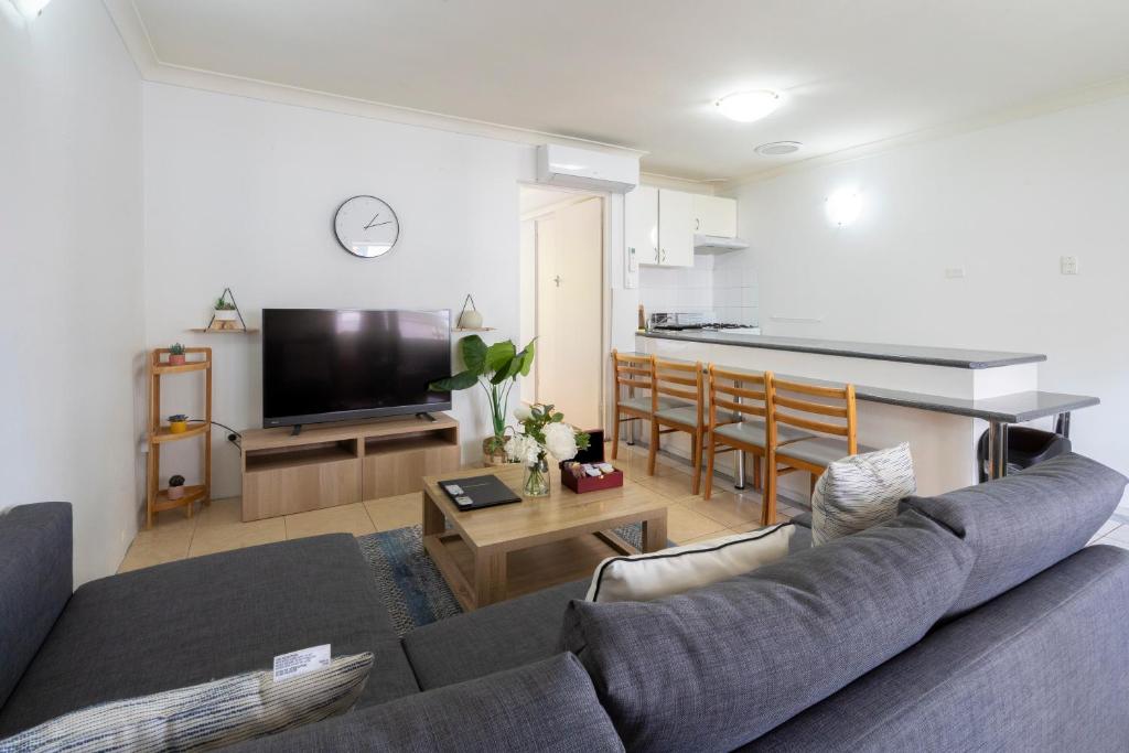 a living room with a couch and a kitchen at Lotus Stay Manly - Apartment 31G in Sydney
