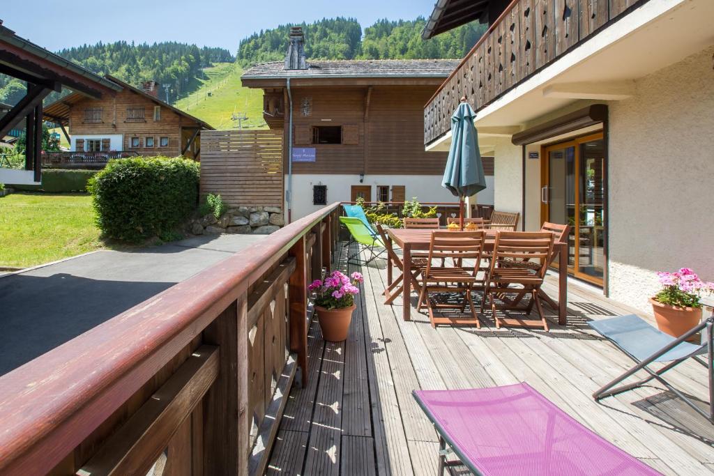 a wooden deck with a table and chairs and an umbrella at Simply Morzine - Chalet Coeur de Morzine in Morzine