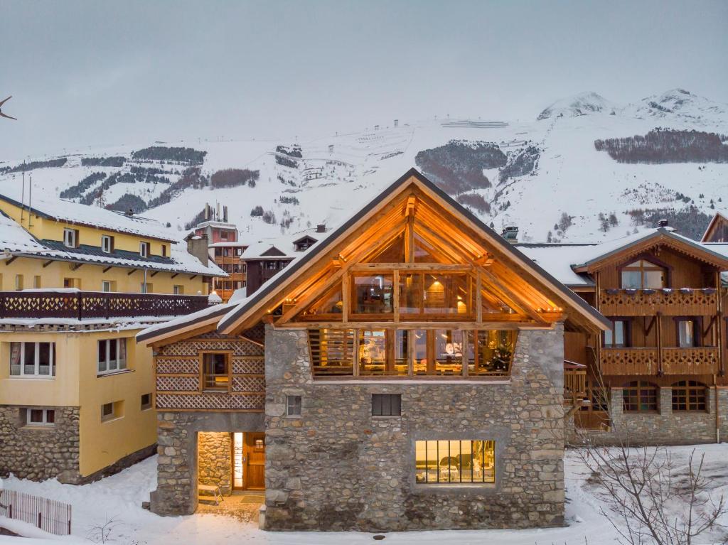 une maison dans la neige avec des montagnes en arrière-plan dans l'établissement Chalet Prestige l'Atelier Lodge, à Les Deux Alpes
