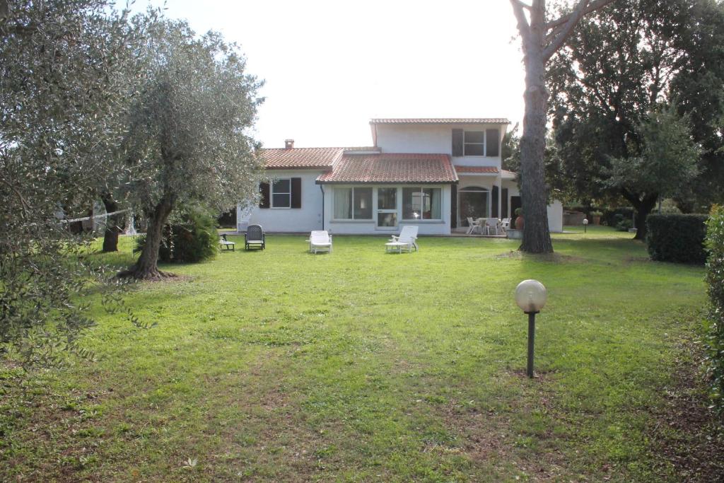 Villa la Respigola completamente indipendente con giardino recintato في دونوراتيكو: بيت فيه ساحه فيها كراسي واشجار