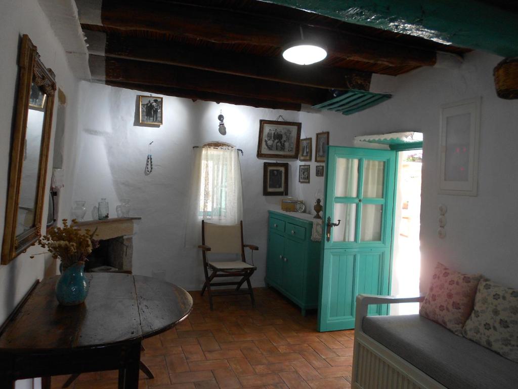 ein Wohnzimmer mit einem Tisch und einer grünen Tür in der Unterkunft Το σπίτι του Παππού. in Patmos