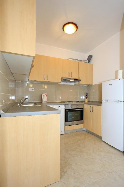 a kitchen with wooden cabinets and a white refrigerator at Apartment Village Nin in Nin