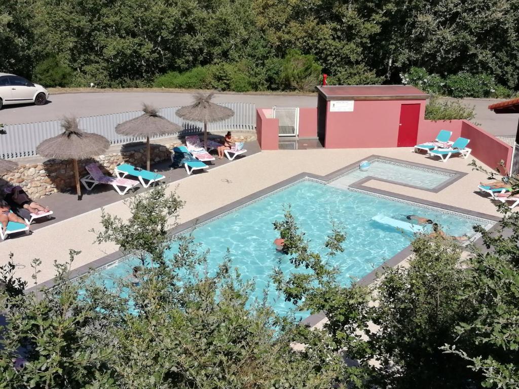 a swimming pool with umbrellas and people sitting around it at Camping Mas Llinas in Le Boulou