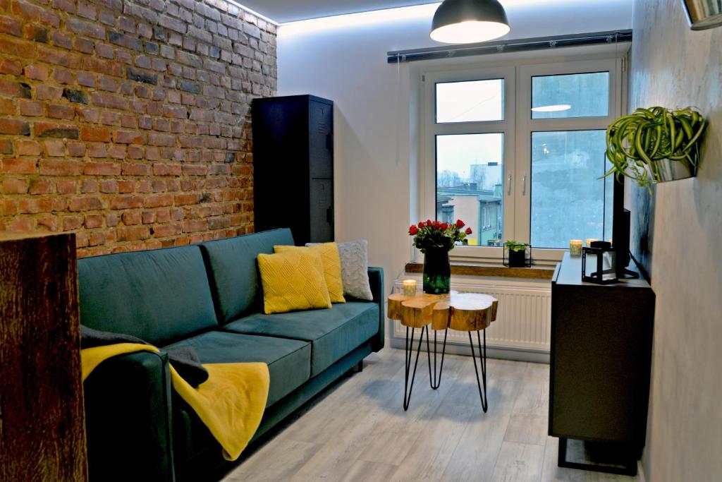 a living room with a blue couch and a brick wall at LOFT MAŁY in Kościerzyna