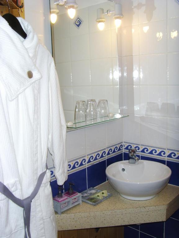 a bathroom with a sink and a white robe at La Ceriseraie in La Gorgue