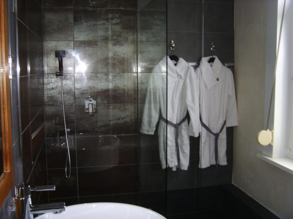 a bathroom with a shower with white clothes hanging at La Ceriseraie in La Gorgue