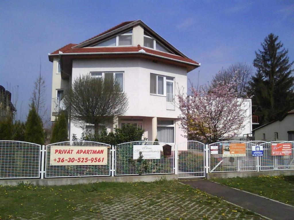 une maison blanche avec une clôture devant elle dans l'établissement Apartman Pávai-Silye, à Hajdúszoboszló