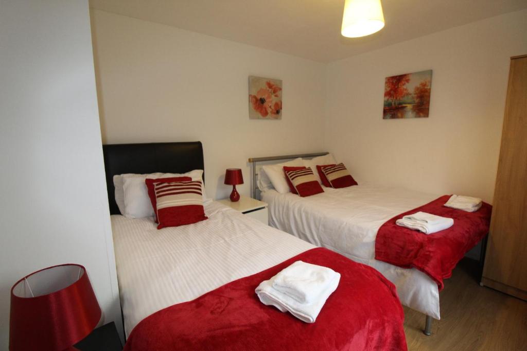 a bedroom with two beds with red and white sheets at Bolsover House in Bolsover