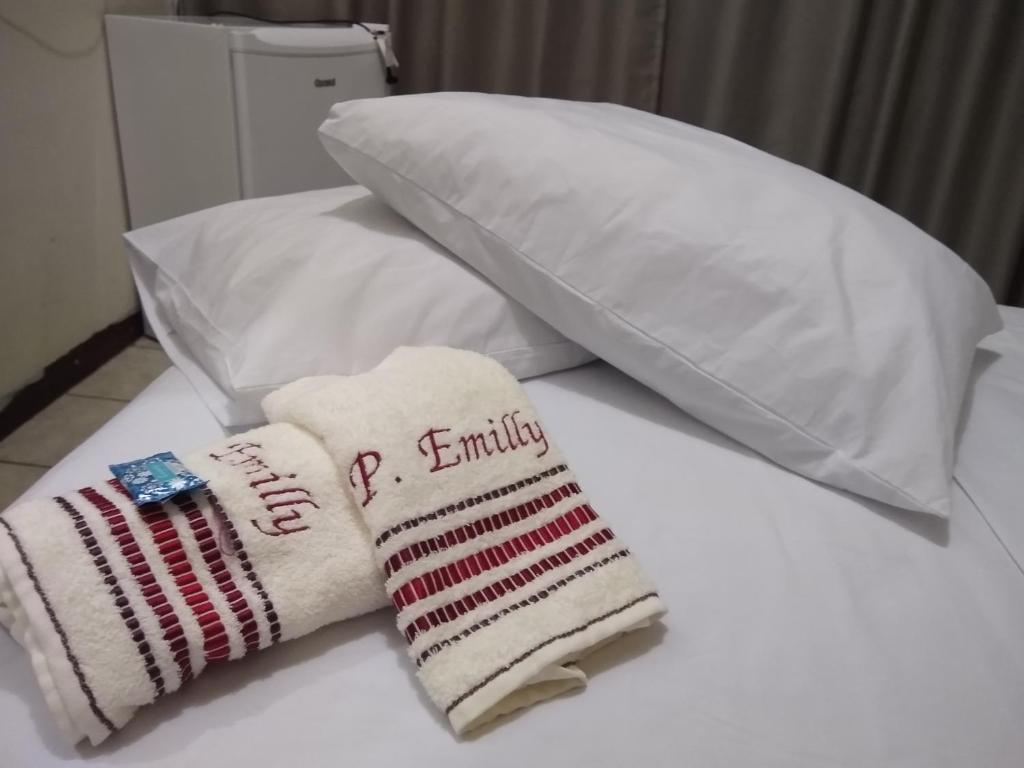 a pile of towels and pillows on a bed at Pousada Emilly in Joinville