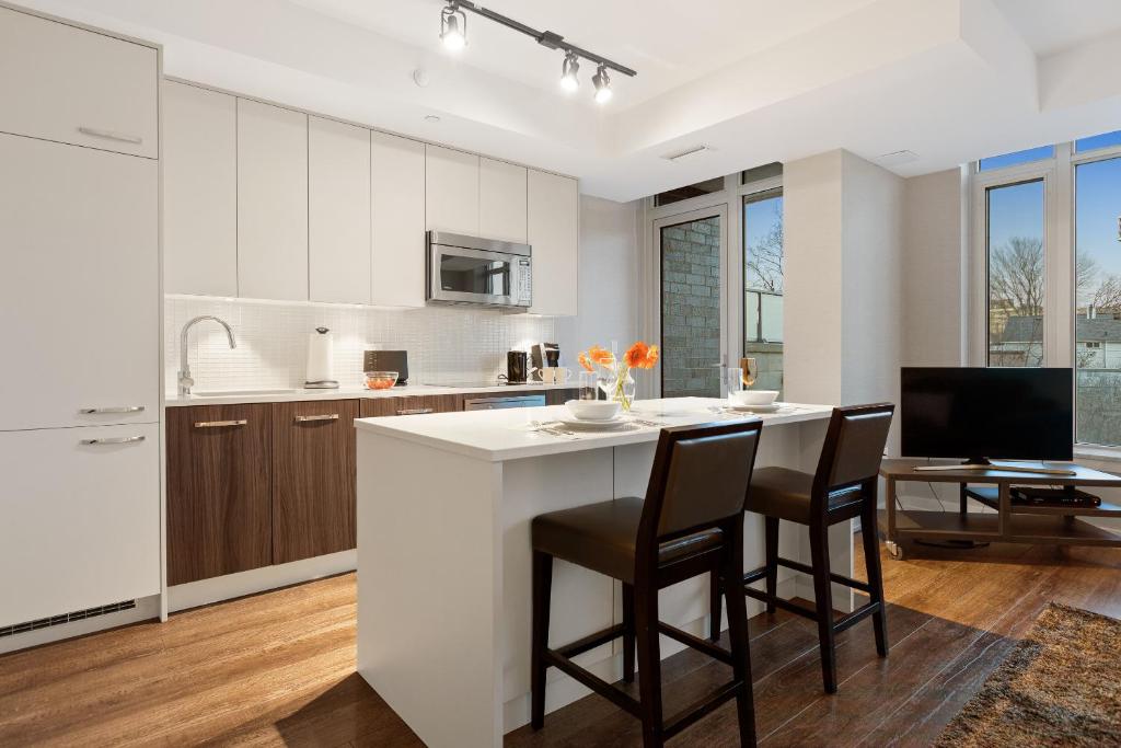 una cocina con una gran isla blanca con sillas en SOHO Residences Champagne en Ottawa