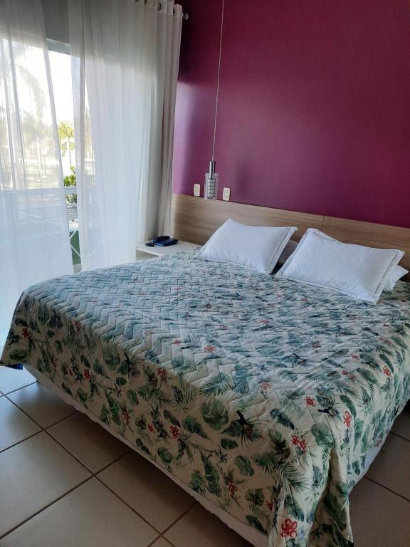 ein Schlafzimmer mit einem großen Bett mit einer lila Wand in der Unterkunft Flat Particular Adeias das Aguas Park Resort in Barra do Piraí