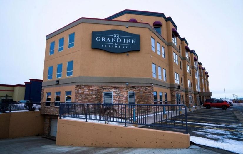 a building with a sign on the side of it at Grand Inn & Residence- Grande Prairie in Grande Prairie