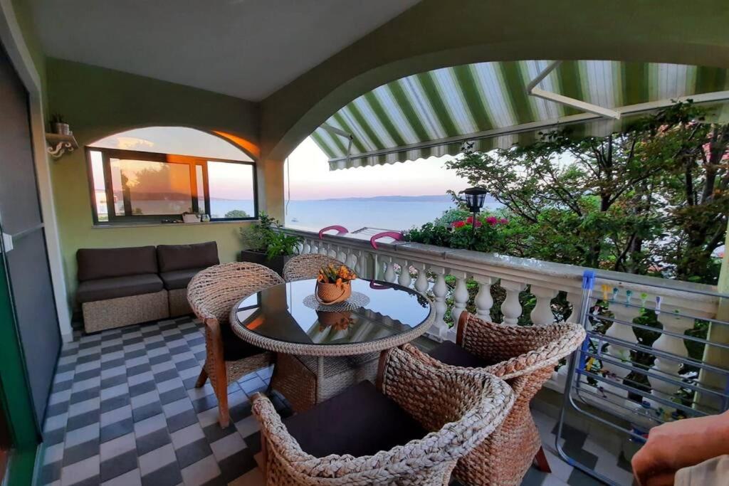 uma varanda com uma mesa e cadeiras com vista para o oceano em Apartman Adrijan em Sukošan