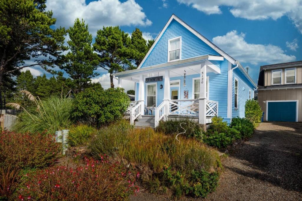 une maison bleue et blanche avec une terrasse couverte dans l'établissement Driftwood Bella Beach, à Depoe Bay