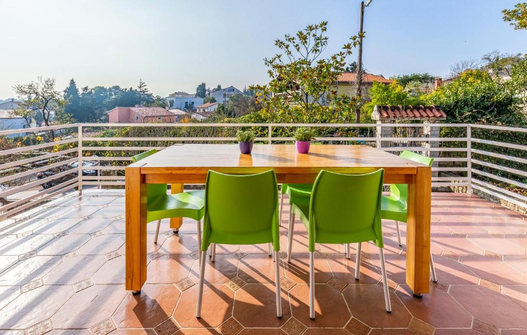uma mesa de madeira e cadeiras verdes numa varanda em Apartments Pimpinella em Premantura