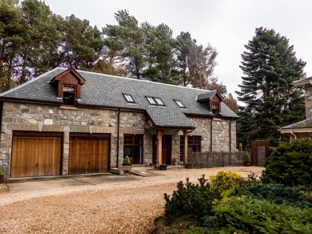 a stone house with a garage and a driveway at Red Squirrel Lodge in Boat of Garten