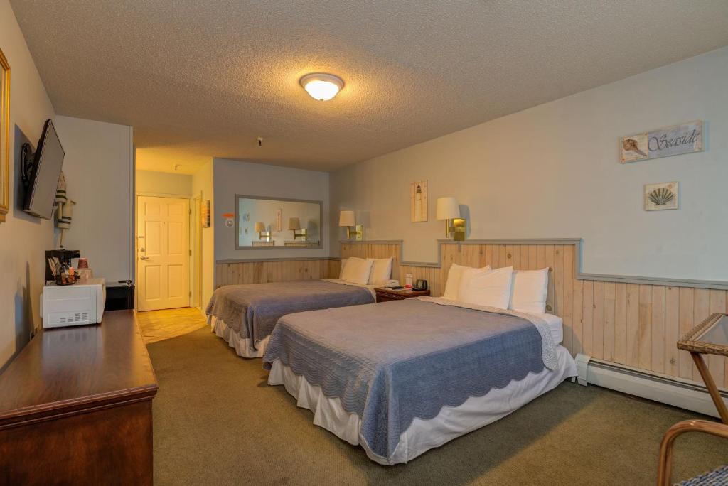 a hotel room with two beds and a television at Vacationland Inn & Suites in Brewer