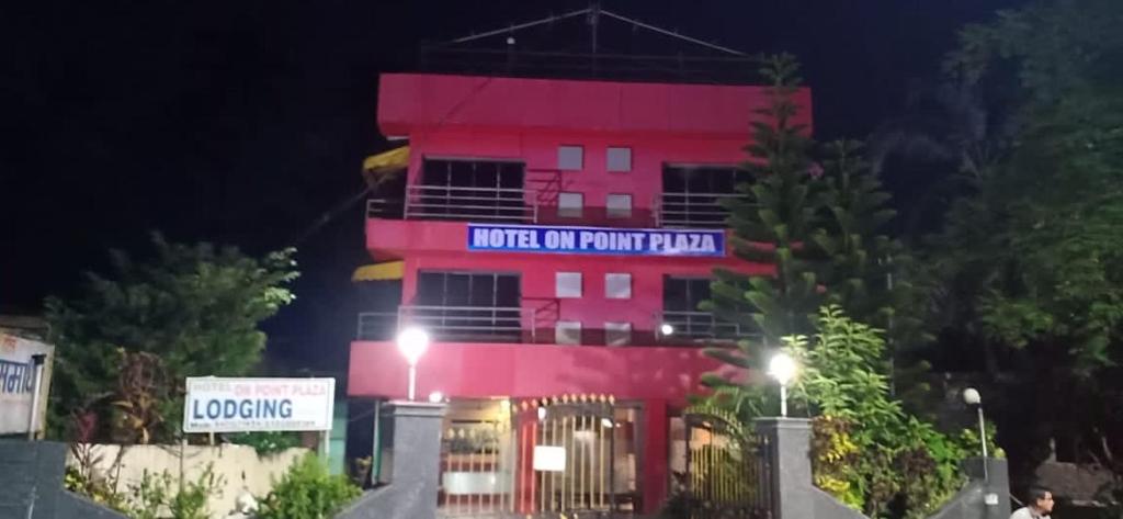 um edifício cor-de-rosa com um cartaz à noite em On Point Plaza em Murud