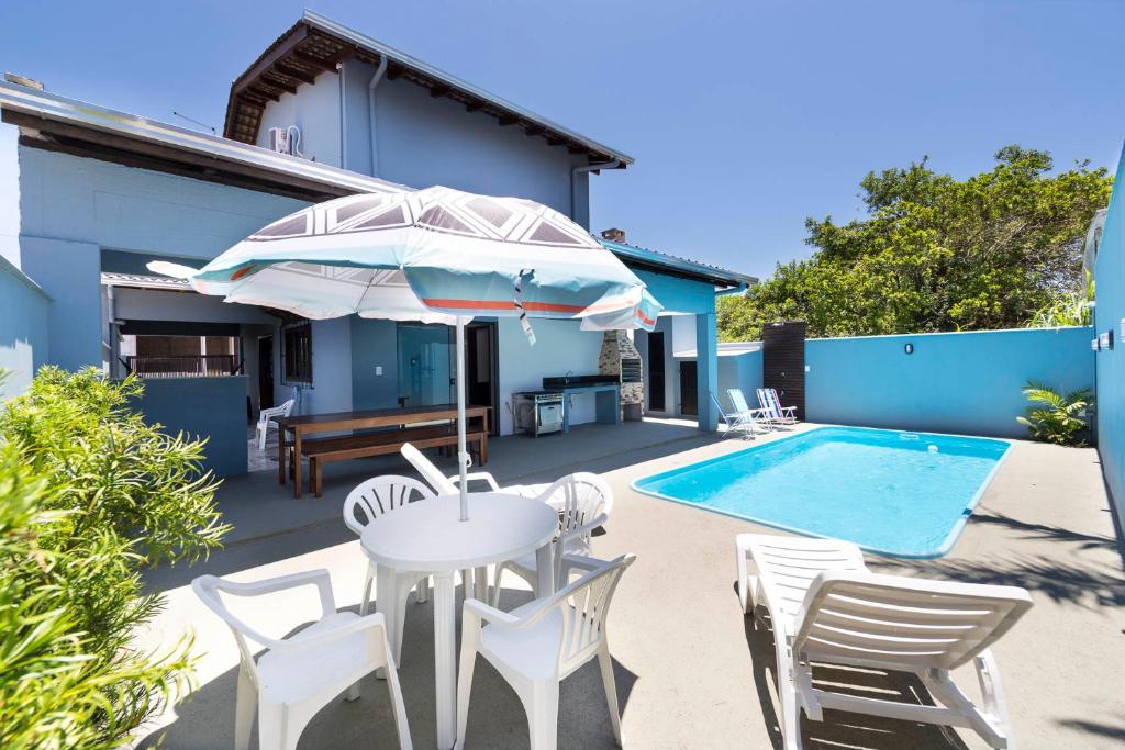 a patio with a table and chairs and a pool at Casa Patta - 05 dormitórios, com piscina. in Bombinhas