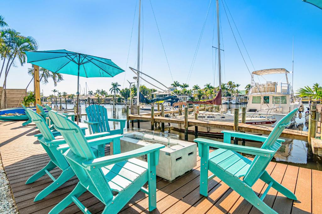 zwei Stühle und ein Regenschirm auf einem Dock mit einem Boot in der Unterkunft Latitude 26 Waterfront Boutique Resort - Fort Myers Beach in Fort Myers Beach