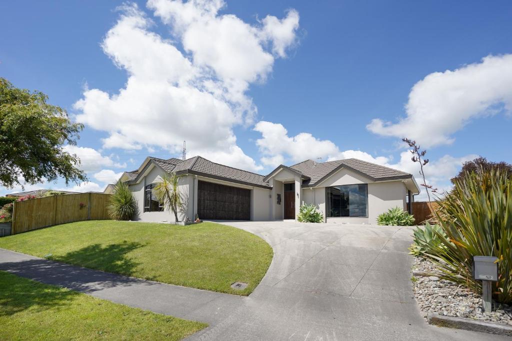 a white house with a fence and a driveway at Ambience on Pacific B&B in Palmerston North