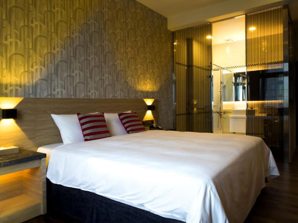 a bedroom with a large white bed with two red pillows at Yu Chun Hotel in Taichung