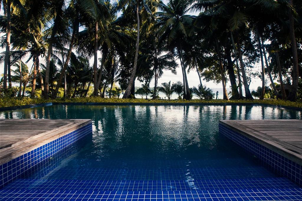a swimming pool with blue tiles and palm trees at Sea Shell Resort & Spa, Havelock in Havelock Island