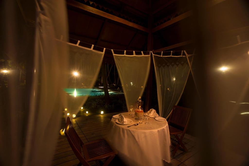 a table in a room with a balcony with lights at Sea Shell Resort & Spa, Havelock in Havelock Island