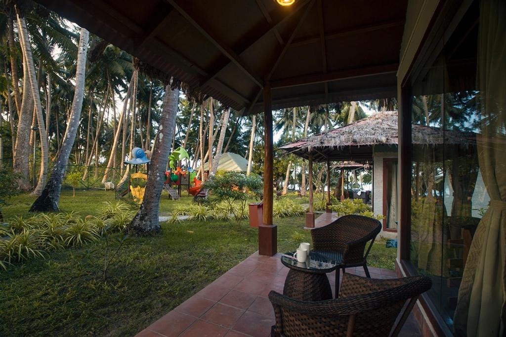 a porch with two chairs and a table with an umbrella at Sea Shell Resort & Spa, Havelock in Havelock Island