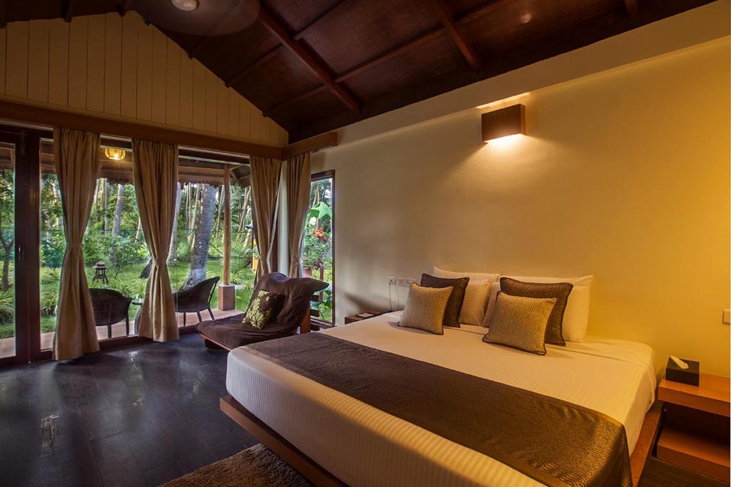 a bedroom with a bed and a large window at Sea Shell Resort & Spa, Havelock in Havelock Island