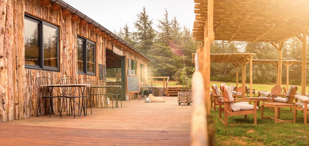 a wooden deck with chairs and tables and a building at Domaine de la Vitarelle Glamping in Villanière