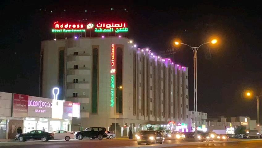 un gran edificio con letreros de neón por la noche en Address hotel Apartments العنوان للشقق الفندقية, en Aş Şa‘arah