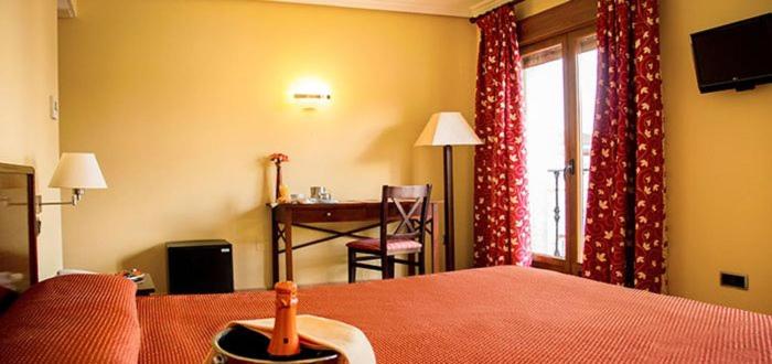 a bedroom with a bed and a desk and a window at Hotel Rural El Jardin in Aldea del Fresno