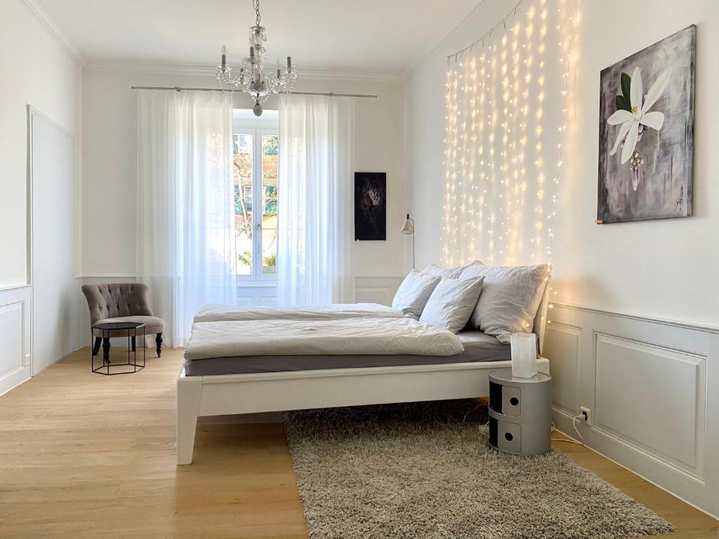 a white bedroom with a bed and a chandelier at Beautiful studio in a villa from 18th century in Thun