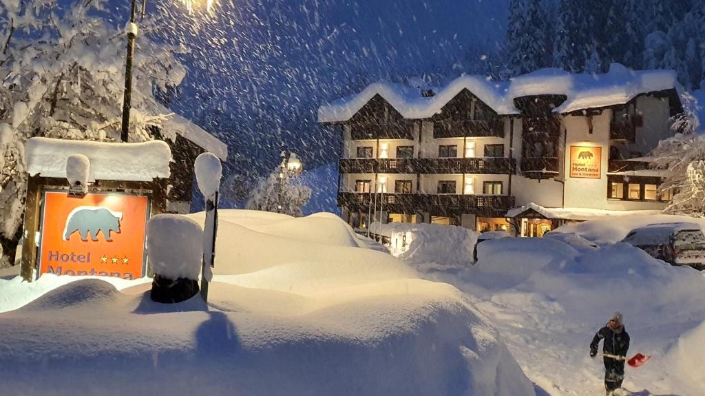 a person standing in the snow in front of a hotel at Hotel Montana in Madonna di Campiglio