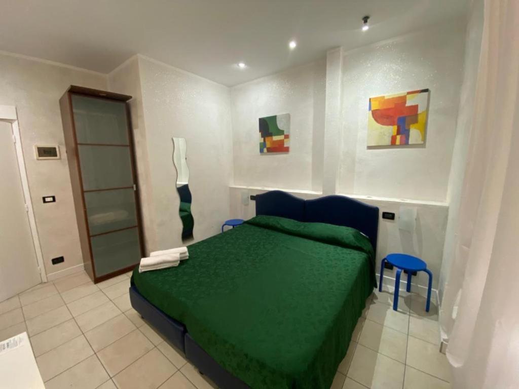 サンレモにあるポロン イン サンレモの緑のベッドと壁に絵画が飾られたベッドルーム1室